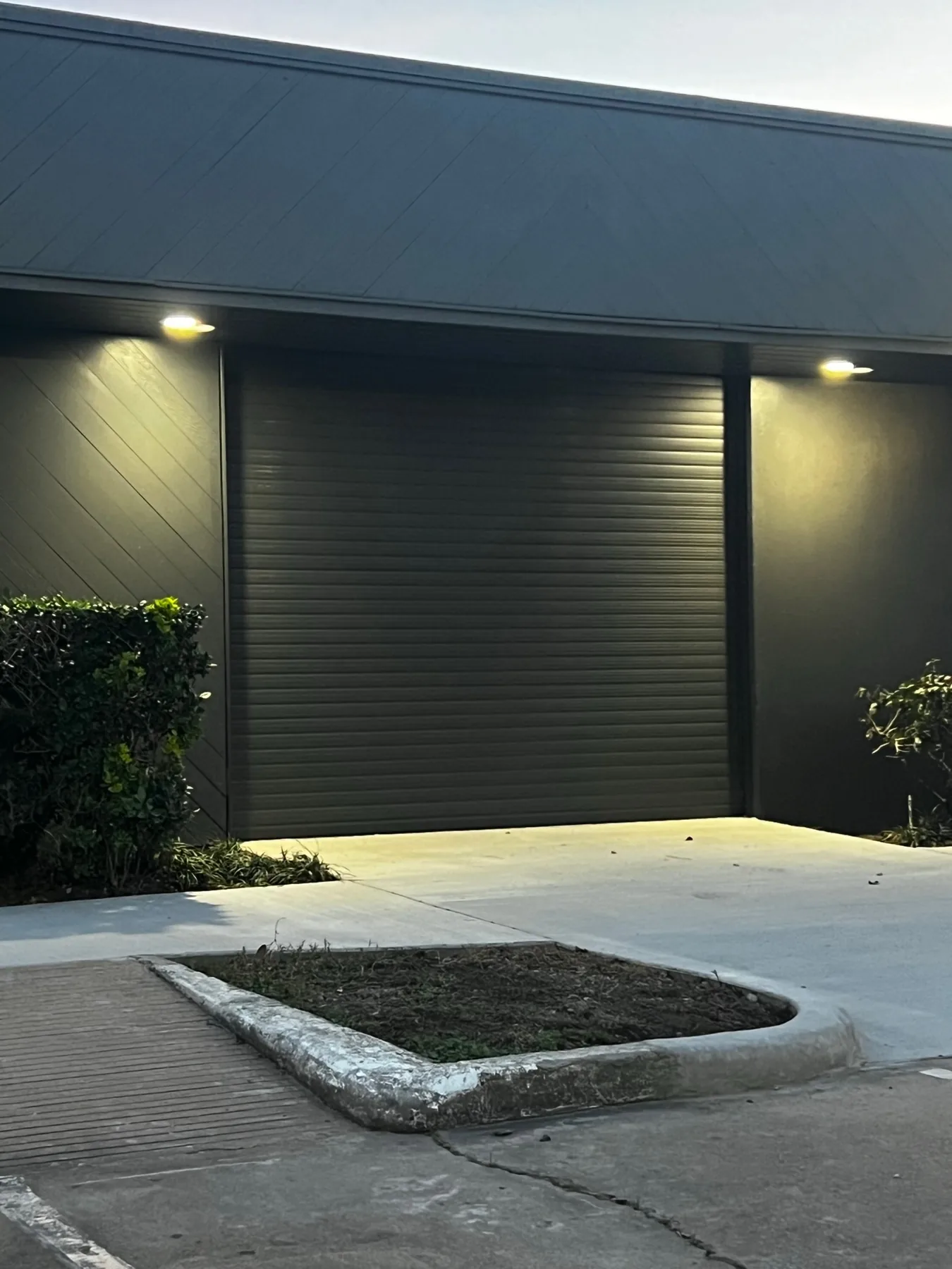 Black roll-up garage door beside a residential entry