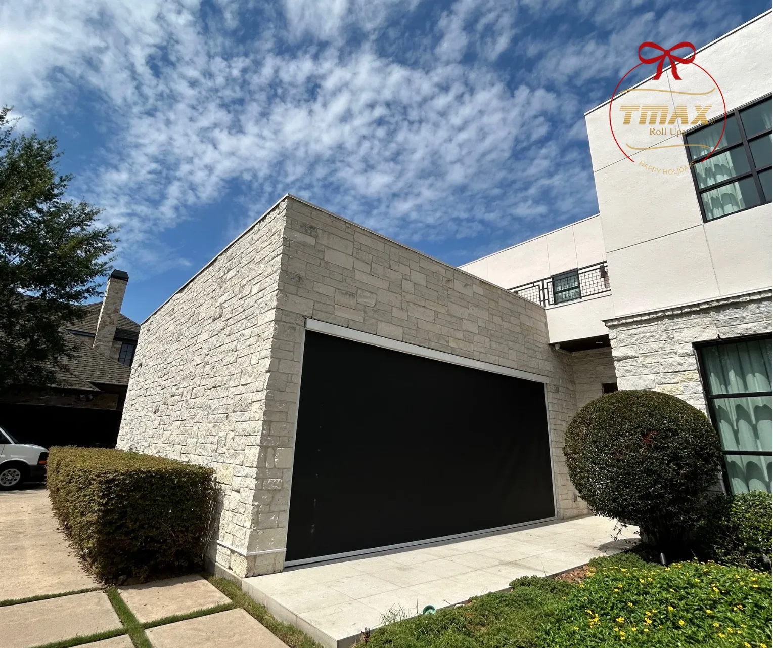 Black TMAX roll-up garage door on a modern white stone home